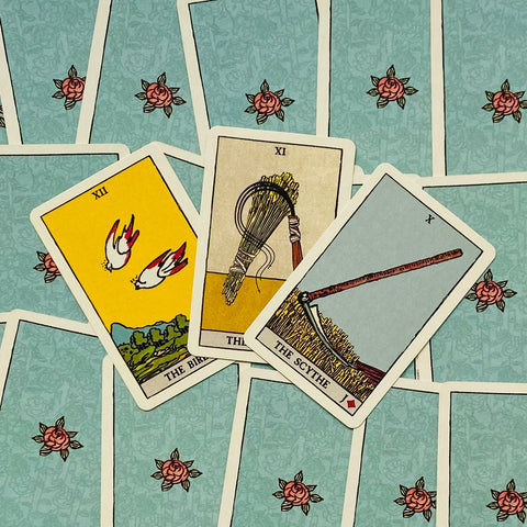 Tarot kortos Rider‑Waite stiliaus, mėlynos rožių nugarėlės, trijų kortų išdėstymas iš viršaus su Scythe, Birds ir Sheaf