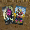Tarot kortos, dvi atviros kortos su ryškiomis violetinėmis kristalų iliustracijomis ant juodo‑auksinio geometrinio fono