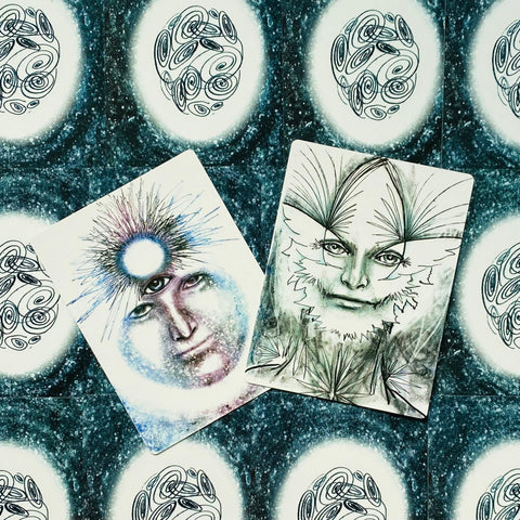 tarot kortos – dvi iliustruotos kortos su mėlynais ir žalsvais veidų motyvais, fotografuotos iš arti; šis variantas skirtas dizaino peržiūrai, skiriasi nuo kitų kortų fone ir piešiniu