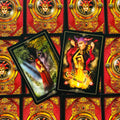 Tarot kortos su dviem atverstomis kortomis – vilko ir liepsnos motyvais, ant raudonų ornamentuotų nugarėlių, dekoratyvus variantas parduotuvės galerijoje