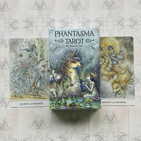 Phantasma Tarot kortų rinkinys su iliustruota dėže centre ir dviem atverstomis kortomis, akvareliniai piešiniai