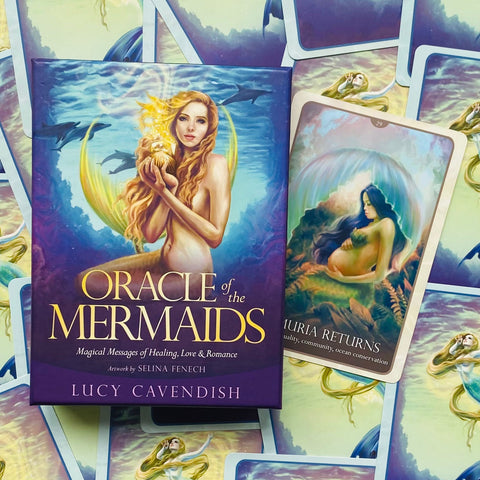 Oracle of the Mermaids kortų kaladė Lucy Cavendish purpuriniame dėkle, matoma dėžutės priekinė iliustracija ir viena atversta korta su nėščia jūros deive