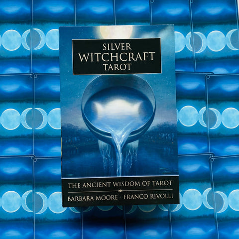 Prekės puslapyje: frontalinis Silver Witchcraft Tarot kortų kaladės mėlynas dėklas ant mėnulio fazių kortų fono, skiriasi nuo kitų kampu nufotografuotų variantų
