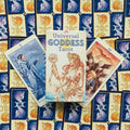 Universal Goddess Tarot dėžutė priekyje, šonuose 9 ir 10 kortos ant mėlynos‑auksinės nugarėlės, centrinis flatlay