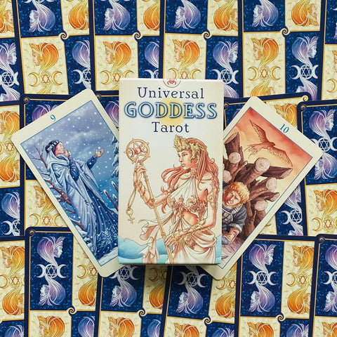 Universal Goddess Tarot dėžutė priekyje, šonuose 9 ir 10 kortos ant mėlynos‑auksinės nugarėlės, centrinis flatlay