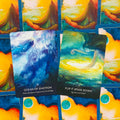 Orakulo kortos su ryškiais mėlynais ir geltonais atspalviais, dvi atverstos kortos (Ocean of Emotion, Flip It Upside Down) ir kortų nugarėlės raštas