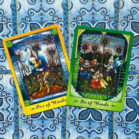 taro kortos, geltonu ir žaliu rėmeliais (Five of Wands ir Six of Wands), pasvirusios viena ant kitos ant mėlyno ornamentuoto audinio, parduodamos pora