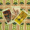 tarot kortos Wild Unknown — trys atvertos kortos (Lazdų tūzas, Lazdų 2, Pentaklių karalius) ant žalsvo ornamentuoto fono
