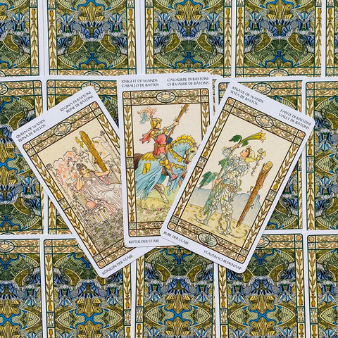 tarot kortos su auksiniais rėmais — trys atvertos kortos centre (riteris, karalienė, tarnas), dekoratyvios žali‑mėlynos nugarėlės