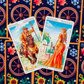 Tarot kortos su dviem Lazdų rūšies kortomis (Riteris ir Princesė), ryškūs oranžiniai atspalviai ant dekoratyvaus audinio