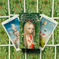 Tarot kortos Nicoletta Ceccoli — žalia dėžutė su mergaitės iliustracija ir dvi atverstos kortos, rodantis serijos unikalius piešinius