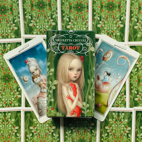 Tarot kortos Nicoletta Ceccoli — žalia dėžutė su mergaitės iliustracija ir dvi atverstos kortos, rodantis serijos unikalius piešinius
