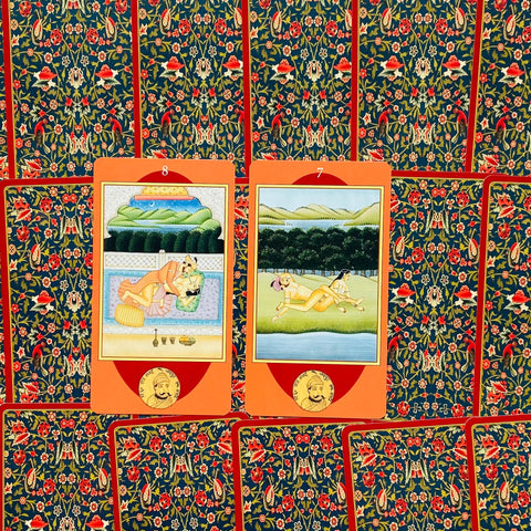 tarot kortos Indijos stiliaus, dvi atidengtos oranžinės kortos (8 ir 7) centre ant tamsiai mėlyno gėlių rašto fono