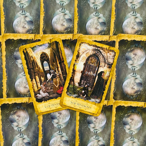 Tarot kortos su geltonais auksiniais rėmeliais, atverstos 5 ir 6 pentaklų kortos ant išdėstytos mėnulio nugarėlių