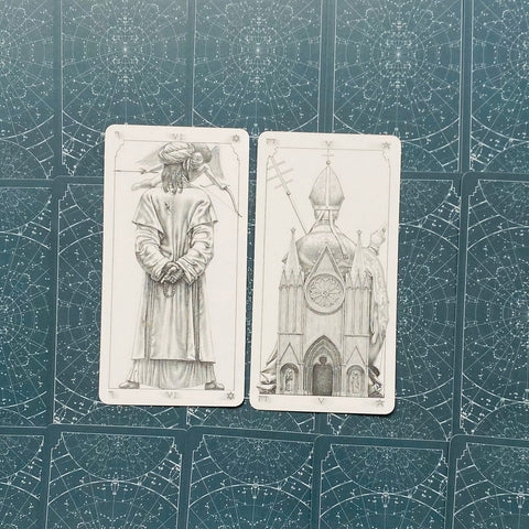 Tarot kortos, du pilkšvai piešti arkano variantai – vienas su apsiaustu ir rožančiu, kitas su katedra, dėliotos ant žvaigždėto fono
