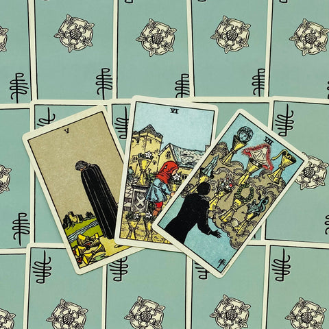 tarot kortos Rider–Waite stiliaus, trijų kortų išklotinė su V, VI ir VII taurėmis, atverstos ir suplotos ant melsvų nugarėlių, rodantis variantą be visos kaladės