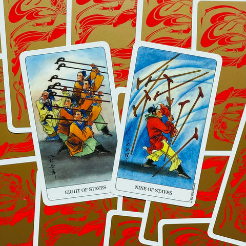 Tarot kortos Kinų stiliaus lazdelės, spalvotos aštuoneto ir devintuko kortos atverstos virš raudonai auksinių nugarėlių, rodoma komplekto variacija