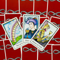 Tarot kortos su raudonomis nugarėlėmis, trys atverstos Taurių kortos (Ten of Cups, Page of Cups, Knight of Cups) išdėstytos fane