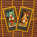 Tarot kortos, atverstos dvi kortos – King of Swords ir King of Wands, sėdinčios ant geltonai-raudono raštuoto nugarėlių fono
