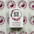 I Ching of Love kortų rinkinys baltame dėkle su purpuriniu simboliu ir vingiuotu žiedu, centre ant yin‑yang fono