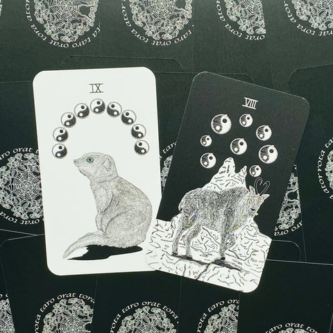 Tarot kortos su gyvūnų iliustracijomis — du atversti variantai (IX katė su žalia akimi ir VIII vilkas su jin‑jang ženklais)