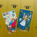 Tarot kortos Symbolon, aukso dėžutės fone dvi skirtingos priekinės kortos su detaliais mitiniais piešiniais, viena pakreipta įstrižai
