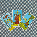 tarot kortos Rider–Waite taurės: trijų kortų išdėstymas iš viršaus ant mėlynos languotos drobės, parodyta kortų variacija