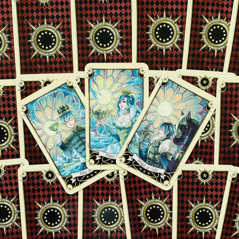 Tarot kortos trys atverstos taurų rūšies kortos (Queen, King, Knight of Cups) ant raudono rombų nugarėlių fono