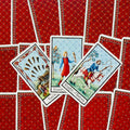 tarot kortos su raudonomis nugarėlėmis, trijų atverstų kortų fanuojantis išdėstymas ir klasikinis iliustracijų stilius