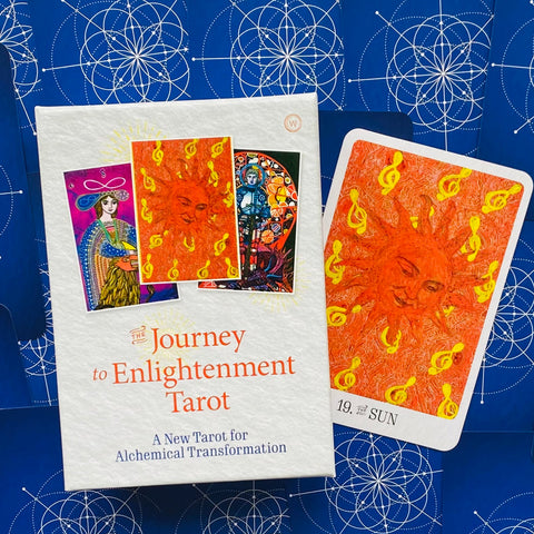 tarot kortos Journey to Enlightenment baltame dėkle su atversta ryškiai oranžine 19‑ąja Saulė korta dešinėje, detalus alchemiškas menas