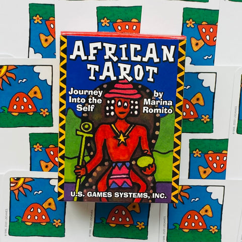African Tarot spalvota dėžutė (U.S. Games Systems) matoma iš priekio virš fanuotų kortų nugarėlių, ryškus artimas kampas