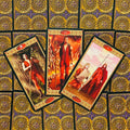 Tarot kortos – trijų kortų išdėstymas su raudonų figūrų iliustracijomis prie auksinių ornamentuotų nugarėlių