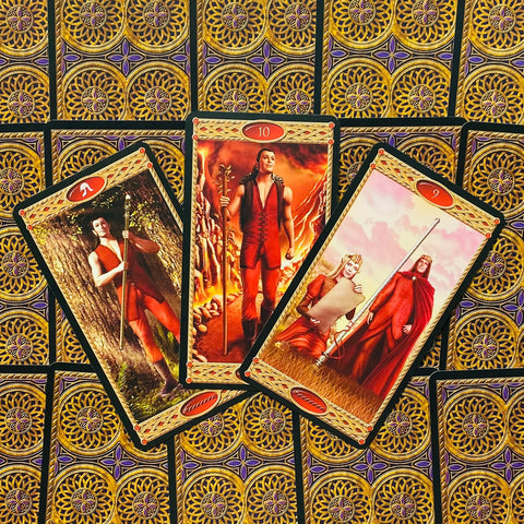 Tarot kortos – trijų kortų išdėstymas su raudonų figūrų iliustracijomis prie auksinių ornamentuotų nugarėlių