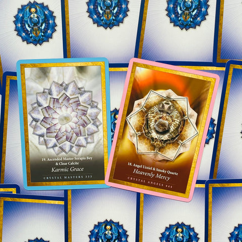 Kortos Crystal Masters ir Crystal Angels, dvi atviros kortos su mėlynu ir rožiniu rėmeliu, kristalų mandalų dizainai, išdėstytos ant kitos kortų eilės