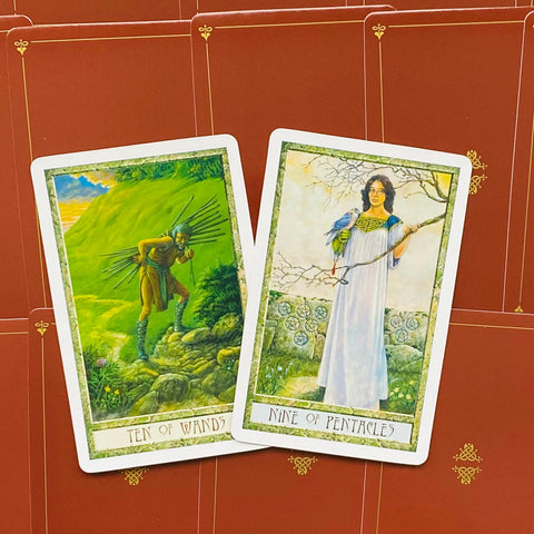 Tarot kortos, dvi atverstos kortos iš arti — Dešimt lazdelės ryškiai žaliame peizaže ir Devyni pentakliai su moterimi