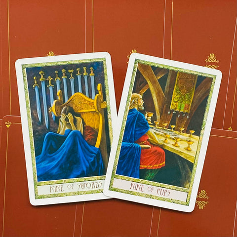 Tarot kortos, dvi atviros kortos (Nine of Swords ir Nine of Cups) su ryškiu raudonu fonu ir baltu rėmeliu, parodytos kampu