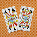 tarot kortos (Marseille stilius) – dvi atviros VII lazdelės su raudonomis lazdomis, mėlynais pynimais ir geltonomis detalėmis ant oranžinio rašto fono