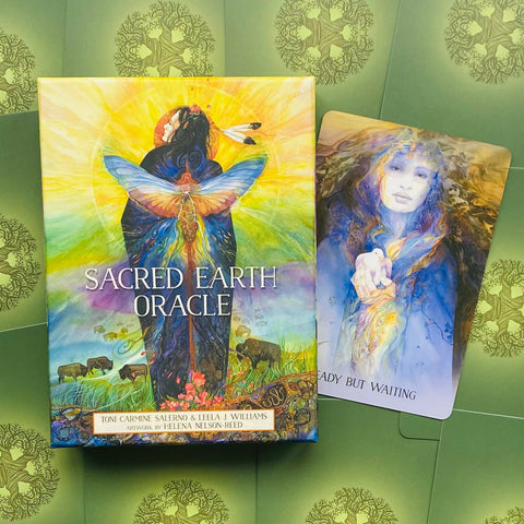Oracle kortos Sacred Earth Oracle – spalvota dėžutė iš priekio su Helena Nelson‑Reed iliustracija ir viena atversta korta šonu, rodanti kortų meninį stilių