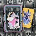 Anime tarot kortų rinkinys – juodos dėžutės priekinis dizainas su rožine anime figūra ir geltoną „Queen of Swords“ kortą, parodo dėžutės bei kortų dizainą pirkėjams