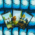 Tarot kortos su mėlynu mėnulio nugarėlės dizainu, atverstos trys kortos su juodais kačių personažais ir liūtu