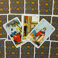 Tarot kortos vintažinių itališkų iliustracijų, trys atrinktos kortos išdėstytos iš priekio ant ornamentuoto nugarėlių fono, ryškios spalvos ir detalės