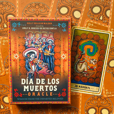 Día de los Muertos orakulo kortos, dekoruota oranžine dėžute ir matoma viena korta šone su aukso/saulėgrąžų raštais