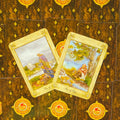 tarot kortos – dvi atverstos taurų kortos (Keturi ir Penki) ant tamsaus ornamentuoto nugarėlių fono, akvareliniai piešiniai