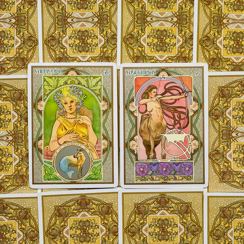 tarot kortos Art Nouveau stiliaus, priekinis planas su Capricorn ir Sagittarius kortomis, auksinės raštuotos nugarėlės fone