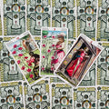 Tarot kortos — trijų Pentaklių kombinacija su rožėmis ir rožinėmis suknelėmis, fanuotos iš viršaus ant dekoratyvių nugarėlių