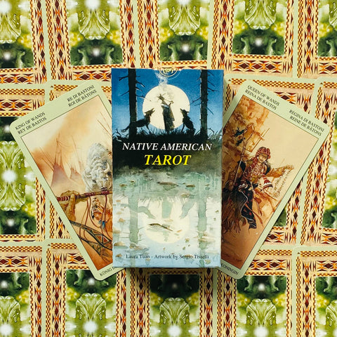 Native American Tarot kortų dėžutė centre, dvi atverstos kortos šone parodytos kampu ant žalio raštuoto fono