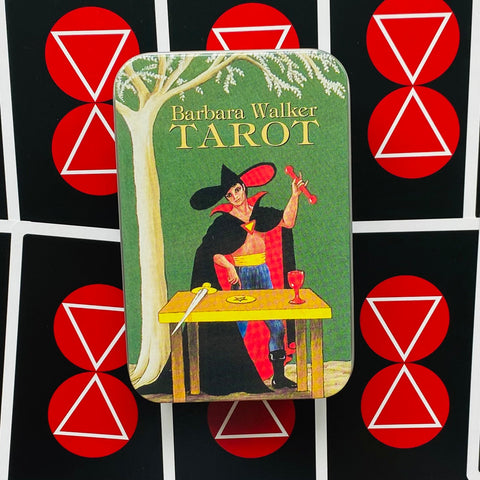 Barbara Walker tarot dėžutė metalinė, žaliu viršeliu su burtininko iliustracija, rodoma iš priekio ant juoda-raudono simbolinio fono
