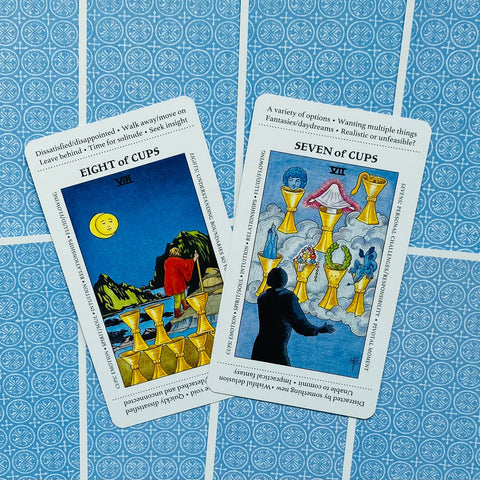 tarot kortos – atverstos Aštuonių taurų ir Septynių taurų kortos ant mėlynos raštuotos nugarėlės, plokščias perspektyvinis kampas