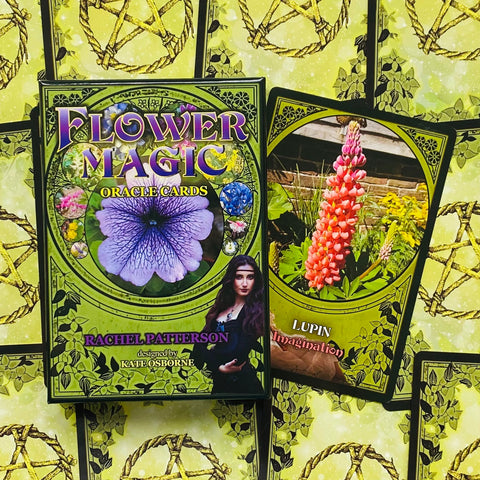 Flower Magic oracle kortos, žalsvoje dėžutėje su violetine gėle ir atidaryta rožinės lupinos korta, rodoma pakuotės ir kortos variante