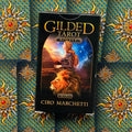 Tarot kortos Gilded Tarot Royale, Ciro Marchetti — juoda priekinė dėžutė ant ornamentuoto mėlyno ir aukso fono